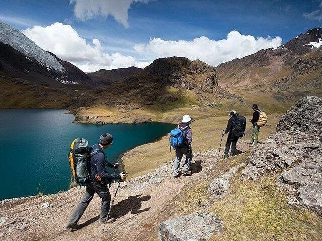 Groupe de randonneurs avec des sacs à dos marchant le long d'un sentier près d'un lac
