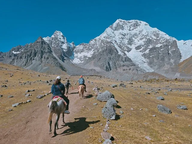 Personnes à cheval sur un sentier vers le mont Ausangate enneigé