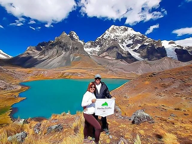 Couple tenant une bannière du Machu Picchu devant un lac bleu